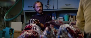 Movie still from “The Thing” (1982), directed by John Carpenter – A man holding a pipe in front of a bunch of plastic bags; Medium shot, Low angle