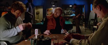 Movie still from “The Thing” (1982), directed by John Carpenter – A man sitting at a table in front of a pool table; Medium shot, Over the shoulder angle