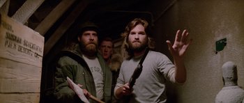 Movie still from “The Thing” (1982), directed by John Carpenter – A group of men standing next to each other in a room; Medium shot, Low angle