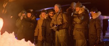 Movie still from “The Thing” (1982), directed by John Carpenter – A group of people standing around a fire; Medium shot, Low angle