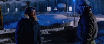 Movie still from “The Thing” (1982), directed by John Carpenter – A man with a beard wearing goggles in the snow; Medium shot, Over the shoulder angle