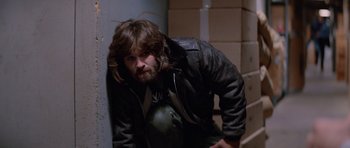 Movie still from “The Thing” (1982), directed by John Carpenter – A man in a leather jacket leaning against a wall; Medium shot, Low angle