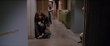 Movie still from “The Thing” (1982), directed by John Carpenter – A man sitting on the ground in an alley; Wide shot, High angle