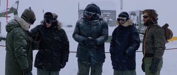 Movie still from “The Thing” (1982), directed by John Carpenter – A group of people standing next to each other in the snow; Medium shot, Low angle