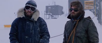 Movie still from “The Thing” (1982), directed by John Carpenter – Two men standing in the snow near a ski lodge; Medium shot, Low angle