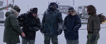 Movie still from “The Thing” (1982), directed by John Carpenter – A group of people standing in the snow wearing winter clothing; Wide shot, Low angle