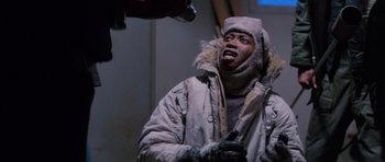 Movie still from “The Thing” (1982), directed by John Carpenter – A man in a winter coat and hat holding a gun; Medium shot, Low angle