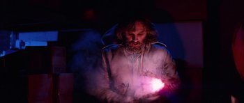 Movie still from “The Thing” (1982), directed by John Carpenter – A bearded man holding a purple light in his hands; Medium shot, Low angle