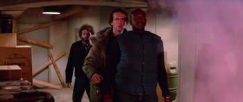 Movie still from “The Thing” (1982), directed by John Carpenter – A group of men standing next to each other in a room; Medium shot, Low angle