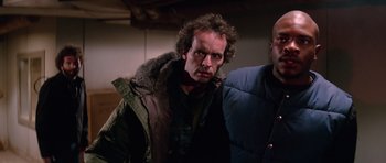 Movie still from “The Thing” (1982), directed by John Carpenter – A man in a jacket and jacket standing next to another man; Close Up shot, Low angle