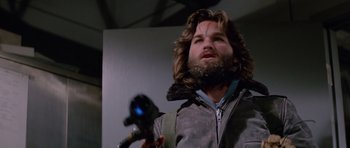 Movie still from “The Thing” (1982), directed by John Carpenter – A man with long hair and a beard holding a camera; Close Up shot, Low angle