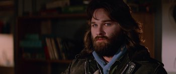 Movie still from “The Thing” (1982), directed by John Carpenter – A man with long hair and a goatee stares into the camera; Close Up shot, Low angle