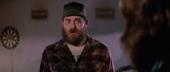 Movie still from “The Thing” (1982), directed by John Carpenter – A man with a beard wearing a green hat; Close Up shot, Over the shoulder angle