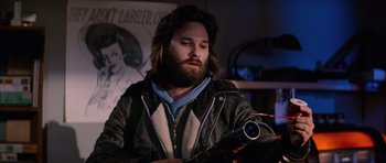 Movie still from “The Thing” (1982), directed by John Carpenter – A man with long hair and a beard holding a video camera; Close Up shot, Low angle