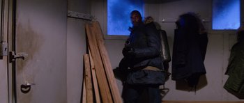 Movie still from “The Thing” (1982), directed by John Carpenter – A man standing in front of a pile of wood in front of a window; Medium shot, Low angle