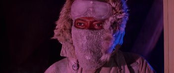 Movie still from “The Thing” (1982), directed by John Carpenter – A man wearing a winter coat and a fur hat and goggles; Close Up shot, Low angle