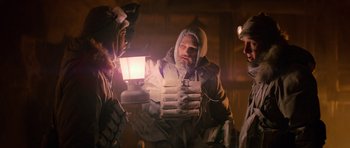 Movie still from “The Thing” (1982), directed by John Carpenter – A group of men standing around a building holding a lantern; Medium shot, Low angle
