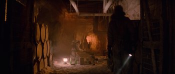 Movie still from “The Thing” (1982), directed by John Carpenter – Two people are standing in a dimly - lit room; Wide shot, Low angle