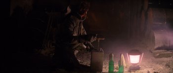 Movie still from “The Thing” (1982), directed by John Carpenter – A man is using an old fashioned machine to make alcohol; Medium shot, Low angle