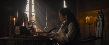 Movie still from “The Three Musketeers - Part I: D'Artagnan” (2023), directed by Martin Bourboulon – A woman sitting at a table writing on a paper; Medium shot, Low angle