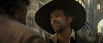 Movie still from “The Three Musketeers - Part I: D'Artagnan” (2023), directed by Martin Bourboulon – A person wearing a hat; Close Up shot, Over the shoulder angle