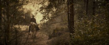 Movie still from “The Three Musketeers - Part I: D'Artagnan” (2023), directed by Martin Bourboulon – A man riding a horse through a forest; Wide shot, Low angle