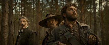 Movie still from “The Three Musketeers - Part I: D'Artagnan” (2023), directed by Martin Bourboulon – A man in a hat standing next to another man in a hat; Medium shot, Low angle