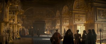 Movie still from “The Three Musketeers - Part I: D'Artagnan” (2023), directed by Martin Bourboulon – People are standing in a large room in a castle like setting; Extreme Wide shot, Low angle