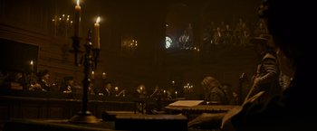 Movie still from “The Three Musketeers - Part I: D'Artagnan” (2023), directed by Martin Bourboulon – A group of people sitting in a room with candles in front of them; Wide shot, Low angle