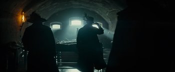 Movie still from “The Three Musketeers - Part I: D'Artagnan” (2023), directed by Martin Bourboulon – A person in a dark room with a hat on; Wide shot, Low angle