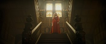 Movie still from “The Three Musketeers - Part I: D'Artagnan” (2023), directed by Martin Bourboulon – A woman in a long red dress standing on some stairs; Wide shot, Low angle