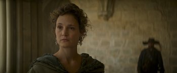 Movie still from “The Three Musketeers - Part I: D'Artagnan” (2023), directed by Martin Bourboulon – A woman in a green dress with a stone wall in the background; Close Up shot, Over the shoulder angle