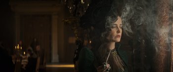 Movie still from “The Three Musketeers - Part I: D'Artagnan” (2023), directed by Martin Bourboulon – A woman smoking a cigarette while wearing a green dress; Close Up shot, Low angle