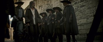 Movie still from “The Three Musketeers - Part I: D'Artagnan” (2023), directed by Martin Bourboulon – A group of men standing next to each other holding guns; Wide shot, Low angle