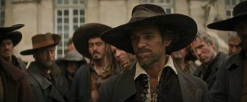Movie still from “The Three Musketeers - Part I: D'Artagnan” (2023), directed by Martin Bourboulon – A group of men wearing hats and standing in a row; Medium shot, Over the shoulder angle