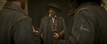 Movie still from “The Three Musketeers - Part I: D'Artagnan” (2023), directed by Martin Bourboulon – A man in a hat and a long coat looking into the mirror; Medium shot, Over the shoulder angle