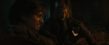 Movie still from “The Three Musketeers - Part I: D'Artagnan” (2023), directed by Martin Bourboulon – Two men sitting in the dark in a forest; Medium shot, Over the shoulder angle