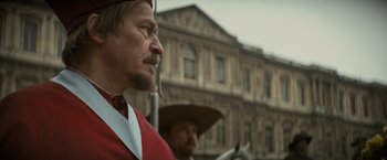 Movie still from “The Three Musketeers - Part I: D'Artagnan” (2023), directed by Martin Bourboulon – A man in a red suit and a man in a brown hat; Close Up shot, Over the shoulder angle