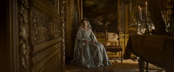 Movie still from “The Three Musketeers - Part I: D'Artagnan” (2023), directed by Martin Bourboulon – A woman dressed in medieval clothing sitting on a chair; Wide shot, Low angle