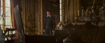 Movie still from “The Three Musketeers - Part I: D'Artagnan” (2023), directed by Martin Bourboulon – A man in a suit standing in front of a mirror; Medium shot, Low angle