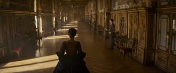 Movie still from “The Three Musketeers - Part I: D'Artagnan” (2023), directed by Martin Bourboulon – A woman in a dress and a man in a red shirt in a room; Wide shot, Over the shoulder angle