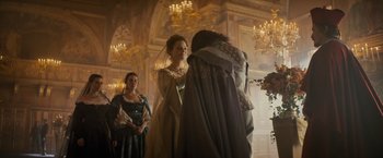 Movie still from “The Three Musketeers - Part I: D'Artagnan” (2023), directed by Martin Bourboulon – Two women in medieval garb standing in front of a chandelier; Medium shot, Low angle