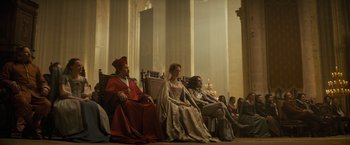 Movie still from “The Three Musketeers - Part I: D'Artagnan” (2023), directed by Martin Bourboulon – A group of people sitting in a room with candles; Wide shot, High angle