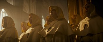 Movie still from “The Three Musketeers - Part I: D'Artagnan” (2023), directed by Martin Bourboulon – A group of people dressed as monks standing in a room; Medium shot, Low angle
