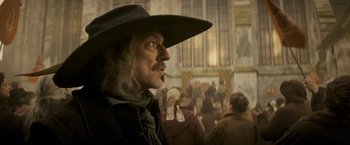 Movie still from “The Three Musketeers - Part I: D'Artagnan” (2023), directed by Martin Bourboulon – A man with a long beard wearing a black hat; Close Up shot, Low angle