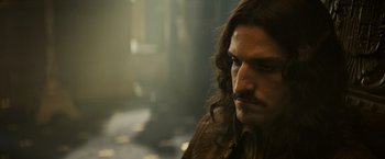 Movie still from “The Three Musketeers - Part I: D'Artagnan” (2023), directed by Martin Bourboulon – A person with long brown hair; Close Up shot, Over the shoulder angle