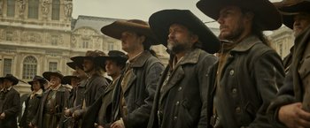 Movie still from “The Three Musketeers - Part I: D'Artagnan” (2023), directed by Martin Bourboulon – A group of men wearing hats and jackets; Medium shot, Low angle