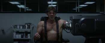 Movie still from “The Tomorrow War” (2021), directed by Chris McKay – A shirtless man is using a machine to work out; Medium shot, Low angle