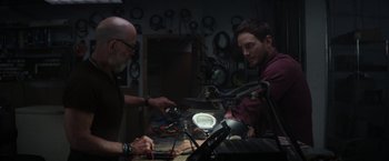 Movie still from “The Tomorrow War” (2021), directed by Chris McKay – Two men working in a shop with a lot of wires in front of them; Medium shot, Over the shoulder angle