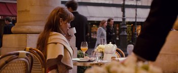 Movie still from “The Tourist” (2010), directed by Florian Henckel von Donnersmarck – A woman sitting at an outdoor table drinking coffee; Medium shot, Over the shoulder angle